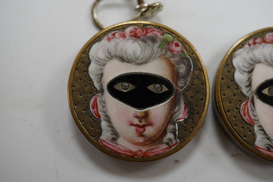 A pair of engraved gilt metal enamel and paste set disc shaped buttons)converted to earrings, one fitting missing), each decorated with a lady wearing a mask, diameter 25mm. Condition - poor to fair